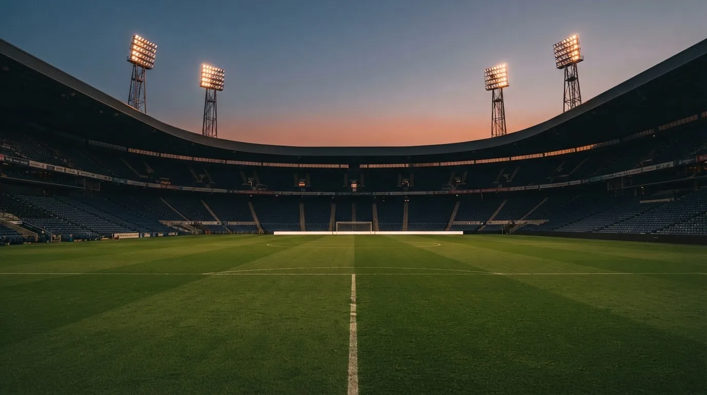 Een leeg voetbalstadion met lichtmasten bij schemering