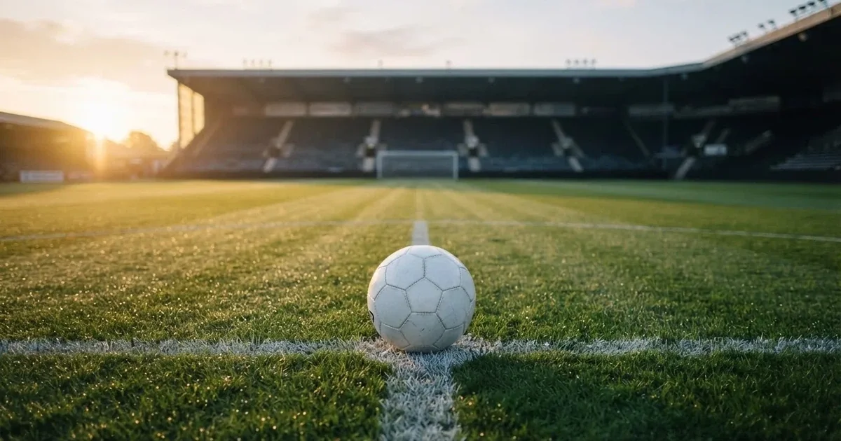 Een voetbal op de middenstip van een grasveld in het ochtendlicht
